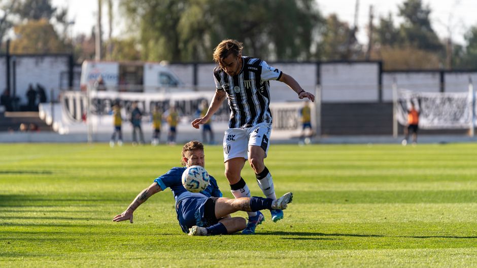 Exciting football tackle scene during a match on a sunny day in a professional stadium.
