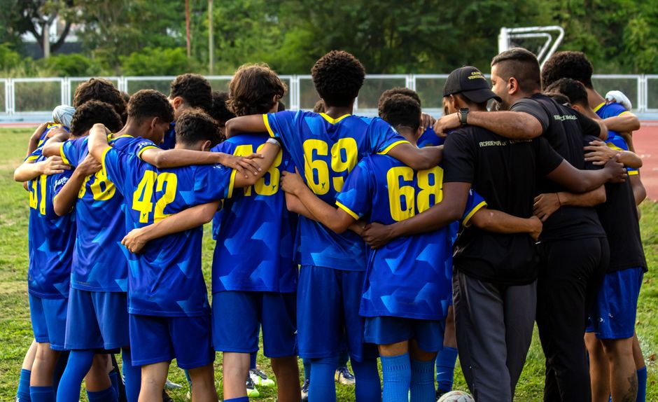 A vibrant moment of unity as a youth football team huddles at a Caracas stadium.
