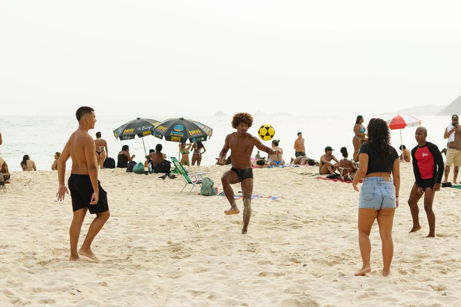 A lively beach scene captures people playing volleyball in Rio de Janeiro's sunny beach setting.
