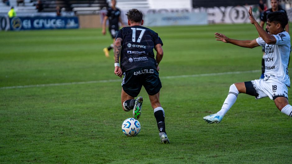 Dynamic moment captured during a soccer match with player dribbling past opponent on a green field.