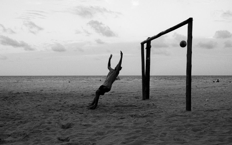 Captivating black and white photo of beach soccer in Natal, Brazil during twilight.