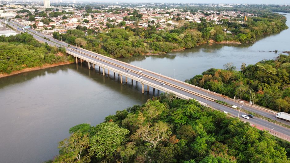 Drone shot capturing a bridge over a river surrounded by lush greenery in Cuiabá, MT, Brazil.