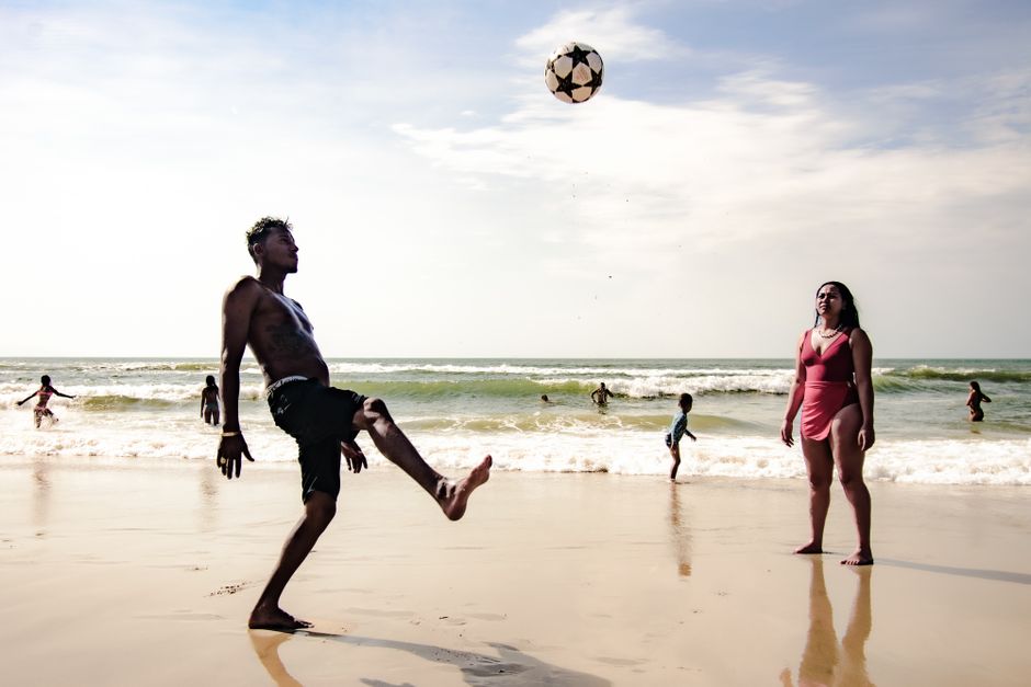 People enjoying a lively day at the beach in São Paulo, playing soccer by the sea.