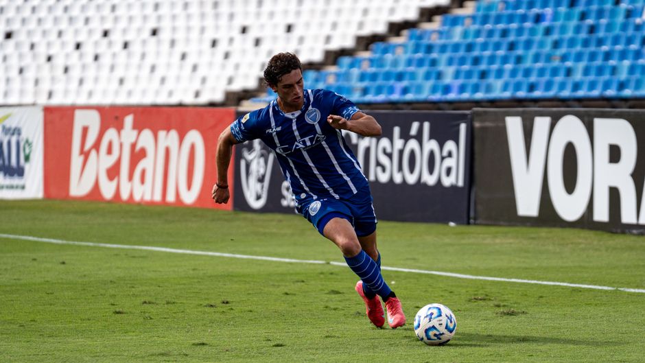 Soccer player dribbling the ball during a match on a sunny day.