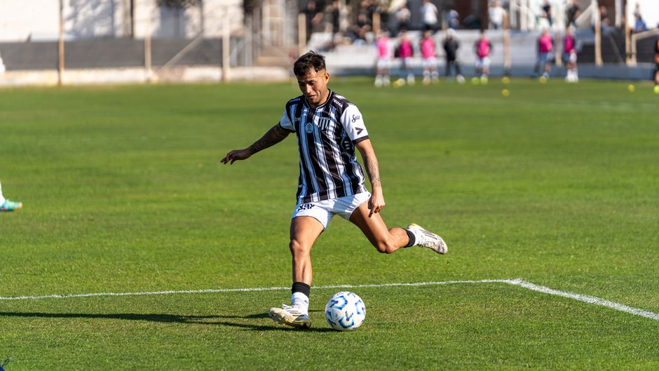 Football player in action kicking ball on a sunny outdoor soccer field.